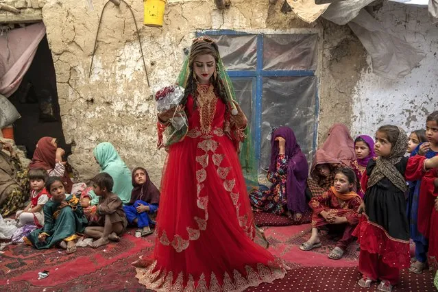 Shamila, 15, from an internally displaced family, adjusts her wedding dress in an old mud house yard, on her wedding day, on the outskirts of Kabul, Afghanistan, Friday, May 19, 2023. “I have no choice. If I don’t accept, my family will be hurt”, she says. Due to poverty and debt, her father had to marry her to a boy at a young age. Her father said that if I did not do this, I might have to give my daughter to someone that I owe. Now, with the money I received from the boy's family, I can pay my debt and treat my son. (Photo by Ebrahim Noroozi/AP Photo)