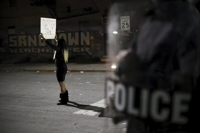 A woman holds a "Justice for Freddie" sign next to graffiti that reads, "Sandtown Winchester" near Baltimore Police Department Western District during a protest against the death in police custody of Freddie Gray in Baltimore April 25, 2015. (Photo by Sait Serkan Gurbuz/Reuters)
