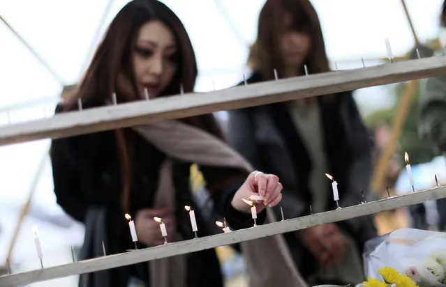 A woman lights a candle to mourn for the victims of the March 11, 2011 earthquake and tsunami prior to a special memorial event Friday, March 11, 2016.  Japan on Friday marked the fifth anniversary of the 2011 tsunami that killed more than 18,000 people and left a devastated coastline along the country's northeast that has still not been fully rebuilt. (Photo by Eugene Hoshiko/AP Photo)