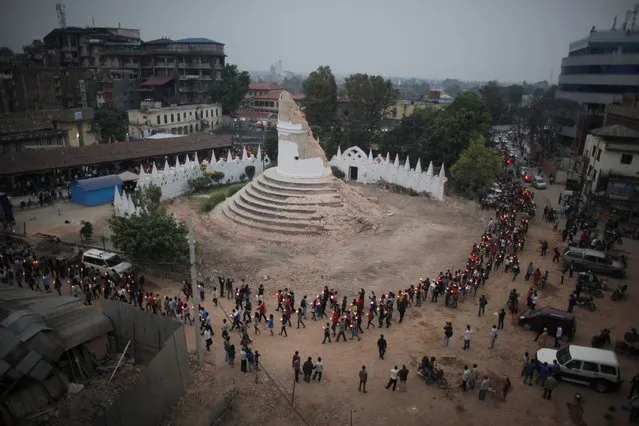 Nepalese people pay tributes to the victims of the April 25 earthquake, as they walk with lighted candles past the destroyed landmark Dharahara tower in Kathmandu, Nepal, Thursday, May 7, 2015. The quake killed thousands and injured many more as it flattened mountain villages and destroyed buildings and archaeological sites in Kathmandu. (Photo by Niranjan Shrestha/AP Photo)