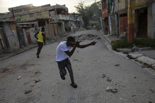 A gang member points an imaginary weapon at a rival on a corner that serves as a divider between gang-controlled territories, in the Bel Air neighborhood of Port-au-Prince, Haiti, Tuesday, October 5, 2021. (Photo by Rodrigo Abd/AP Photo)