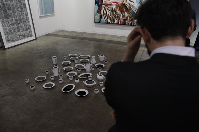 A man looks at an artwork “Black Milk” created by Israeli sculptor Belu-Simion Fainaru during the VIP preview of the art fair “Art Basel” in Hong Kong, Tuesday, March 22, 2016. (Photo by Kin Cheung/AP Photo)