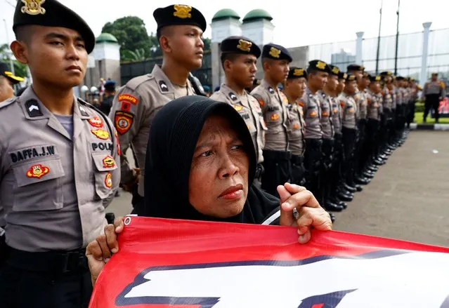 An anti-government protester stands in front of police officers during a rally demanding a fair election, outside the Indonesian parliament in Jakarta, Indonesia, on February 12, 2024. (Photo by Kim Kyung-Hoon/Reuters)