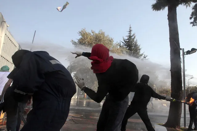 A masked demonstrator throws a petrol bomb towards the police during a protest at the University of Santiago, in Santiago, Chile, Thursday, May 14, 2015. (Photo by Luis Hidalgo/AP Photo)