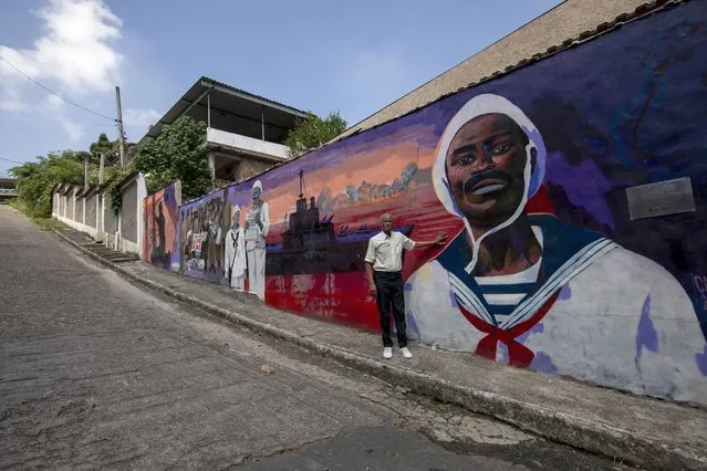Adalberto Cândido poses for a photo in front of a mural that depicts the story of his father João Cândido, a black sailor who led a revolt against the Brazilian Navy, in Sao Joao de Meriti, Rio de Janeiro state, Brazil, Thursday, January 21, 2023. After witnessing a sailor's flogging, Cândido led a revolt against regular whipping by officers in 1910. He and fellow mutineers were tortured, and only two survived – including Cândido. (Photo by Bruna Prado/AP Photo)