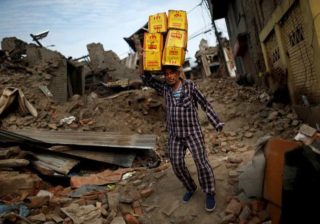 A man carries boxes on his head as he walks next to collapsed houses on the outskirts of Kathmandu,  Nepal, May 15, 2015. (Photo by Ahmad Masood/Reuters)