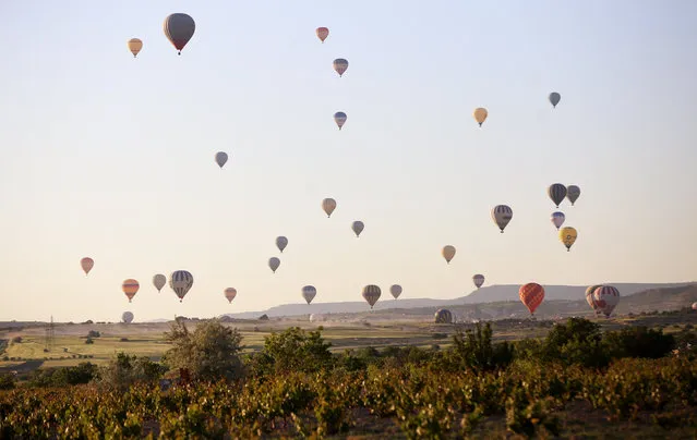 Hot air balloons glide over the historical Cappadocia region, located in Central Anatolia's Nevsehir province, Turkey on May 28, 2019. Cappadocia is preserved as a UNESCO World Heritage site and is famous for its chimney rocks, hot air balloon trips, underground cities and boutique hotels carved into rocks. When weather conditions reach ideal level, 150 hot-air balloons launch every morning at Cappadocia. Tourists view the geographical region formed by interactions of wind and rain with lavas erupted from Mount Erciyes and Hasan. (Photo by Behcet Alkan/Anadolu Agency/Getty Images)