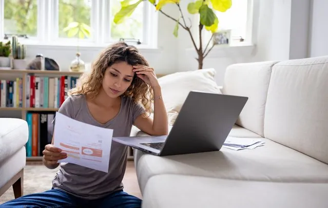 Woman looking worried about her home finances while reading her bank statement – bankruptcy concepts (Photo by Hispanolistic/Getty Images)