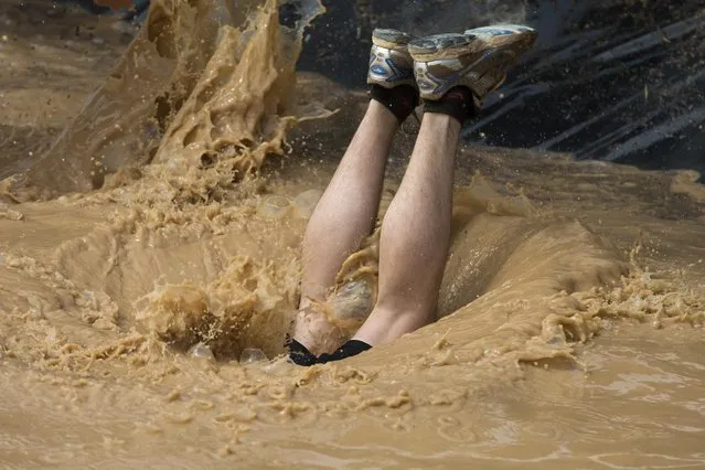 A participant dives into a mud pool while taking part in the Mud Day athletic event in Toledo, Spain, Saturday, May 23, 2015. (Photo by Paul White/AP Photo)