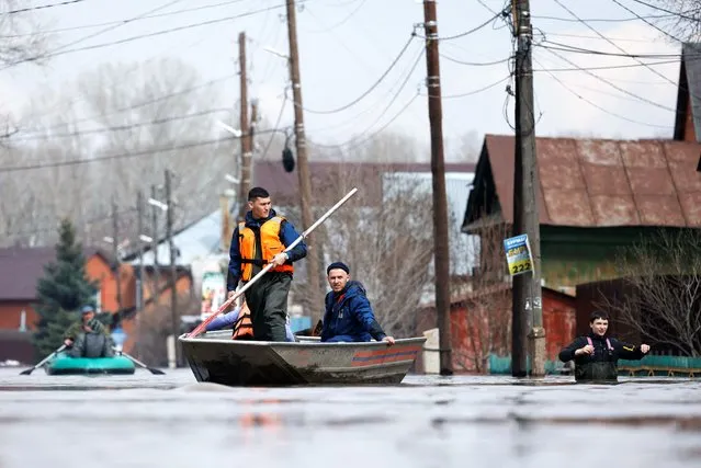 Residents and Russian Emergencies Ministry rescuers ride boats in a flooded street in Orenburg, Russia on April 10, 2024. (Photo by Maxim Shemetov/Reuters)