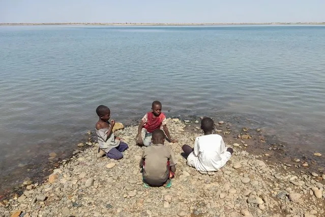 Children sit on the bank of the river Seteit in Gadaref state in eastern Sudan on April 24, 2024. The war in Sudan – which experts have warned could last for years – has pushed 18 million Sudanese into acute food insecurity, five million of whom are on the brink of famine. The international community pledged earlier this week more than two billion euros in aid to Sudan, only half of what the UN demanded, during a meeting in Paris. (Photo by AFP Photo/Stringer)