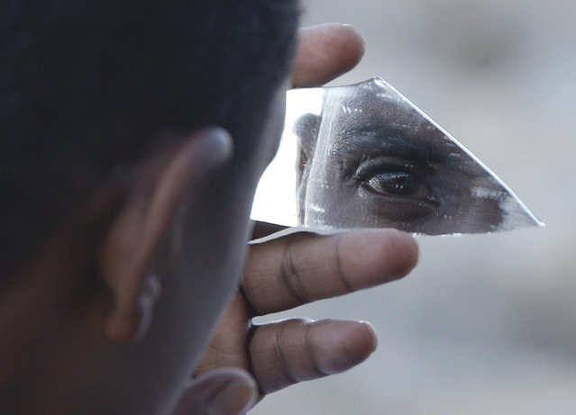 A migrant uses a piece of glass as a mirror as he stands on the rocks of the seawall at the Saint Ludovic border crossing on the Mediterranean Sea between Vintimille, Italy and Menton, France, June 17, 2015. Police on Tuesday began hauling away mostly African migrants from makeshift camps on the Italy-France border as European Union ministers met in Luxembourg to hash out plans to deal with the immigration crisis.     REUTERS/Eric Gaillard