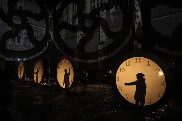 Visitors interact with clock lighting on the “Palace of Stardust” light trail held for the Christmas season at Hampton Court Palace in south west London, Tuesday, December 7, 2021. The River Thames-side palace was a home of King Henry VIII and last used as a royal residence more than 200 years ago. (Photo by Matt Dunham/AP Photo)