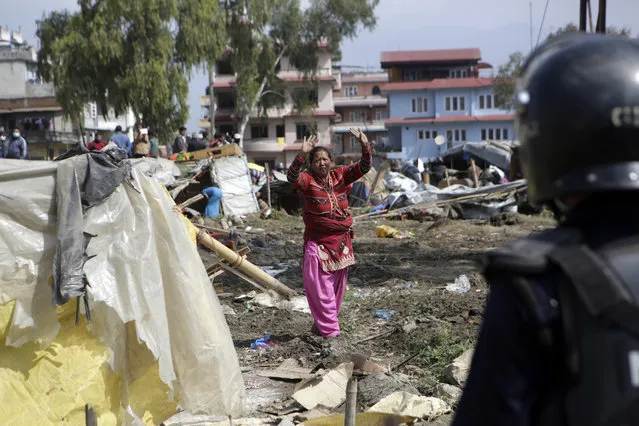 Nepalese woman ask to policeman to stop as they tore down temporary huts in an earthquake shelter in downtown Kathmandu, Nepal, Tuesday, March 14, 2017. Police tore down hundreds of temporary huts in the Nepalese capital where people who lost their homes in the 2015 earthquake have been living for two years. (Photo by Niranjan Shrestha/AP Photo)