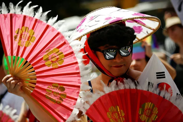 A participant holds fans and a South Korean flag as he walks during the Tokyo Rainbow Pride parade celebrating lesbian, gay, bisexual, and transgender (LGBT) culture in Tokyo, Japan, May 8, 2016. (Photo by Thomas Peter/Reuters)