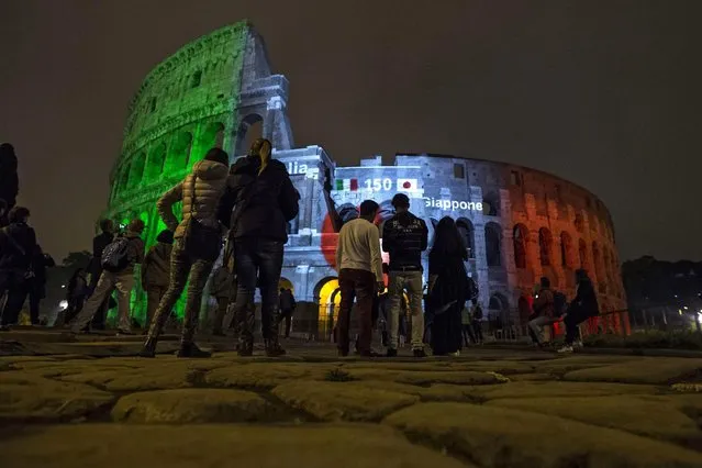 A picture made availble on 12 May 2016 shows people watching the lighting ceremony at the Colosseum in Rome, Italy, 11 May 2016. The ceremony was held to mark the 150th anniversary of relations between Japan and Italy. (Photo by Angelo Carconi/EPA)