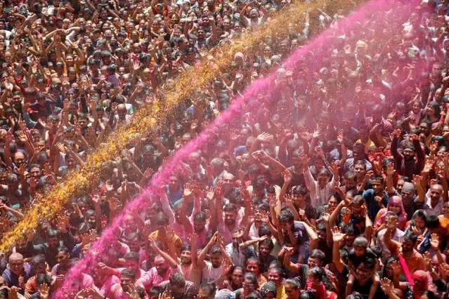 Hindu devotees pray as they are sprayed with coloured water at a temple's premises during Holi celebrations in Ahmedabad, India, March 18, 2022. (Photo by Amit Dave/Reuters)