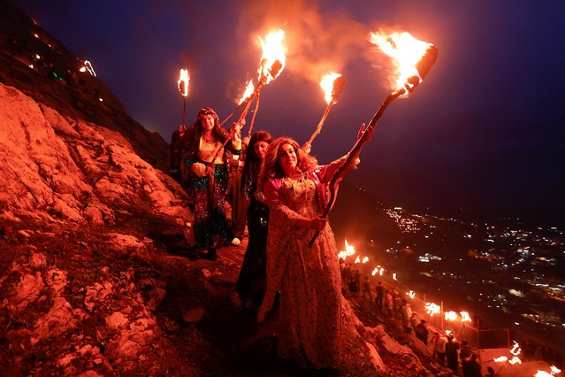 Iraqi Kurdish people carry fire torches, as they celebrate Nowruz Day, a festival marking the first day of spring and Persian New Year, in the town of Akra near Duhok, in Kurdistan, Iraq on March 20, 2023. (Photo by Alaa Al-Marjani/Reuters)