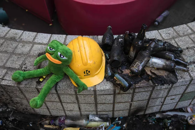 A stuffed toy depicting Pepe the Frog, a character used by pro-democracy activists as a symbol of their struggle, is seen next to a helmet and burnt glass bottles at the Hong Kong Polytechnic University in the Hung Hom district in Hong Kong on November 22, 2019. Hardline Hong Kong protesters held their ground on November 21 in a university besieged for days by police as the US passed a bill lauding the city's pro-democracy movement, setting up a likely clash between Washington and Beijing. (Photo by Dale de la Rey/AFP Photo)