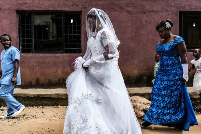 Chinyere (Godgiven) arrives escorted by her maidens of honour for her wedding at the Evangelic Calvary Life Mission Church on May 28, 2017 in the Osusu district of Aba, Nigeria. (Photo by Marco Longari/AFP Photo)