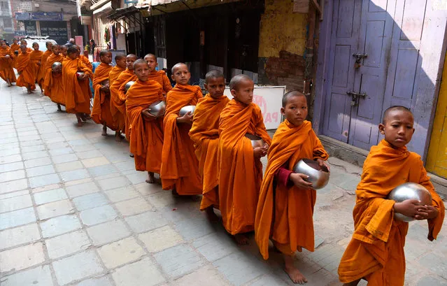 Nepali Buddhist monks hold metal alms pots as they march through an alley near Durbar Square in Kathmandu on November 20, 2019. (Photo by Prakash Mathema/AFP Photo)