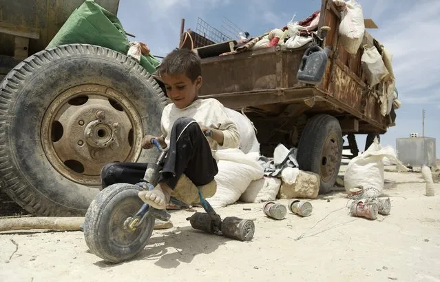 An Iraqi child who fled with his family the northern province of Nineveh following the advance of jihadists of the Islamic State (IS) group, plays with a makeshift tricycle in a refugee camp in al-Hawl located some 14 kilometers from the Iraqi border in Syrias northeastern Hassakeh province, on May 31, 2016. The camp houses some 5000 refugees according to its chief Ciwan Sidou. (Photo by Delil Souleiman/AFP Photo)