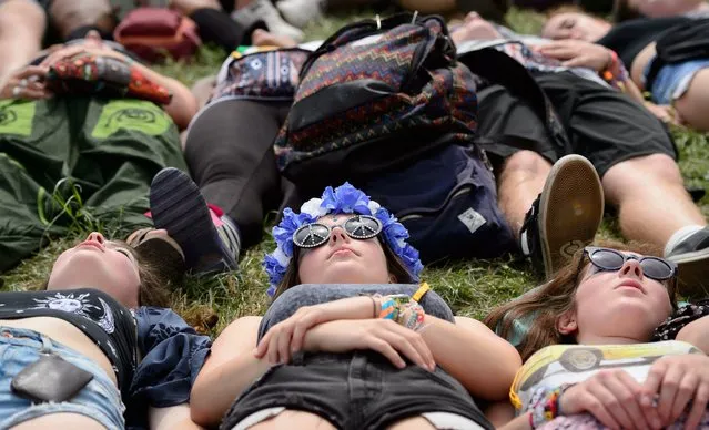 Festival goers take part in an open-air yoga session in the Green Fields, as revellers gather ahead of this weekends Glastonbury Festival of Music and Performing Arts on Worthy Farm near Pilton in Somerset, south west England, on June 26, 2014. (Photo by Leon Neal/AFP Photo)