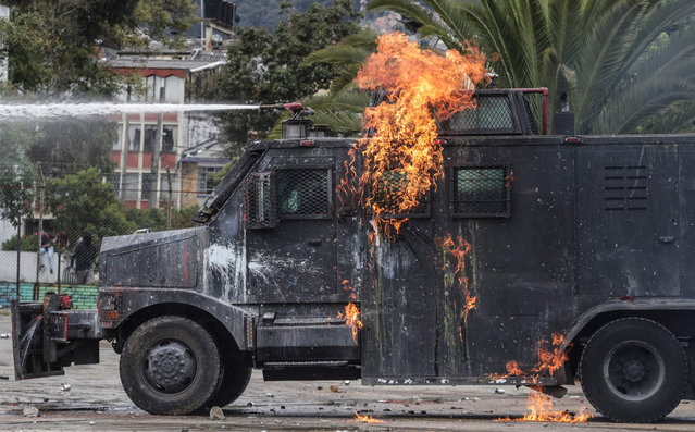 A riot control vehicle is hit by a Molotov cocktail during a protest commemorating the day of the fallen student in Bogota, Colombia on June 8, 2023. (Photo by Juan Pablo Pino/AFP Photo)