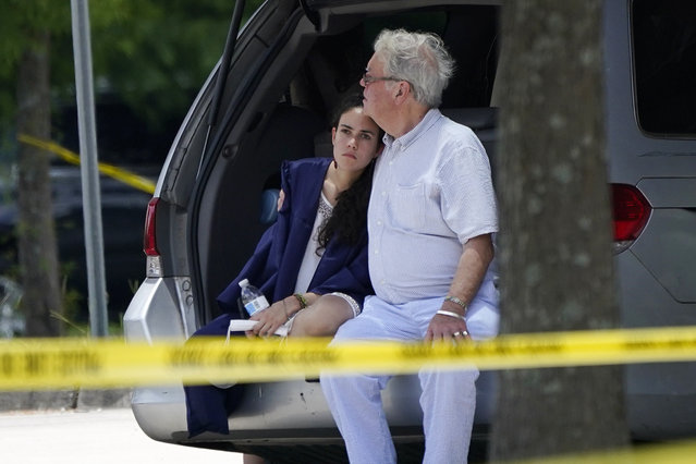 A man comforts a young woman wearing a graduation gown within the crime scene of a shooting at Xavier University in New Orleans, Tuesday, May 31, 2022. (Photo by Gerald Herbert/AP Photo)