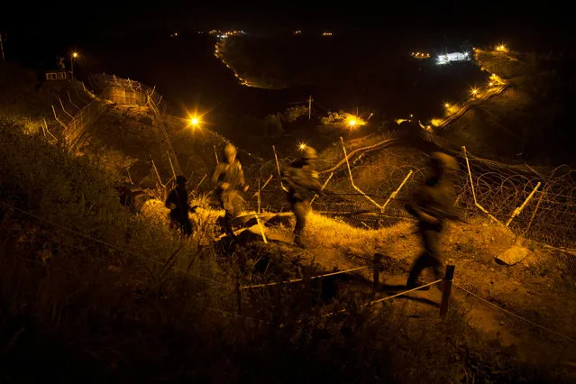 A picture made available on 23 June 2016 and taken with slow shutter speed shows South Korean Army soldiers making a nighttime inspection on the southern side of the Demilitarized Zone (DMZ) dividing the Koreas in Yeoncheon, some 62km north of Seoul, South Korea, 22 June 2016. Upcoming 25 June marks the anniversary of the outbreak of the Korean War in 1950 that technically has never ended since it ended in an armistice, not a peace treaty. (Photo by EPA/Yonhap)