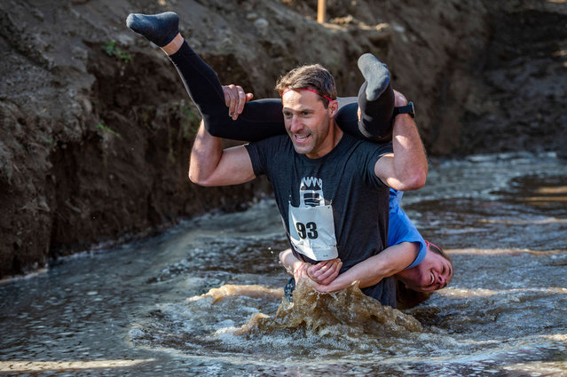 Chad Rowley and his wife Susan race during the 22nd North American Wife Carrying Championship at Sunday River Resort in Newry, Maine, on October 9, 2021. Couples compete on a 278-yard (254-meter) obstacle course for a prize of wife's weight in beer and five times her weight in money. Winners are invited to the world championship in Finland where the sport originated. (Photo by Joseph Prezioso/AFP Photo)