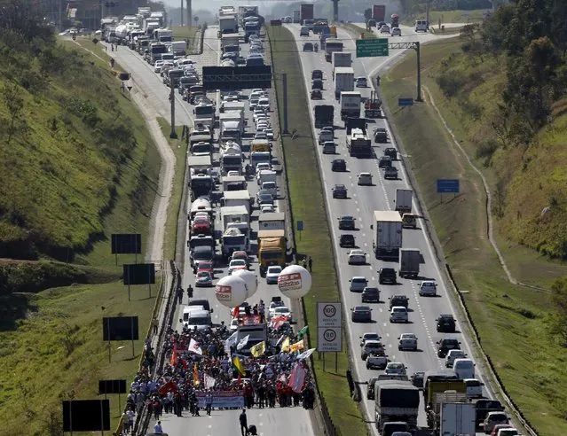 Workers of General Motors march along Dutra highway during a protest against job cuts in Sao Jose dos Campos, Brazil, August 14, 2015. The protest is part of a strike that started on August 10, 2015 paralyzed work at a General Motors plant in Brazil, and the union at a nearby Daimler truck factory threatened to strike over job cuts as labor tensions boiled over in a slumping market. (Photo by Paulo Whitaker/Reuters)
