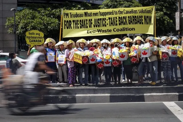 A Filipino motorist passes by environmental activists as they stage a protest against the garbage shipments from Canada outside the Embassy of Canada in Makati City, south of Manila, Philippines, 28 June 2016. According to a statement from the protesting group EcoWaste Coalition, they are calling out to Canadian Prime Minister Justin Trudeau to take back the garbage shipments which have been rotting at the Subic and Manila ports. (Photo by Mark R. Cristino/EPA)