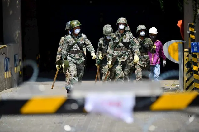 Paramilitary policemen with shovels walk out from a underground garage at a damaged residential area, near the site of the explosions at the Binhai new district, Tianjin, China, August 16, 2015. (Photo by Reuters/China Daily)