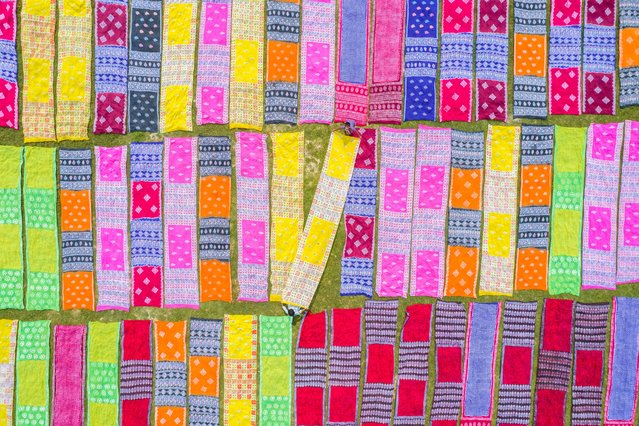 Workers spread colored cloths and sarees on a field to dry under the hot sun after the fabric is dyed at Batik Village at Narayanganj, Bangladesh on September 26, 2024. Once they are dry – which usually takes four hours – they are made into clothes which are sold worldwide. (Photo by Mustasinur Rahman Alvi/Rex Features/Shutterstock)