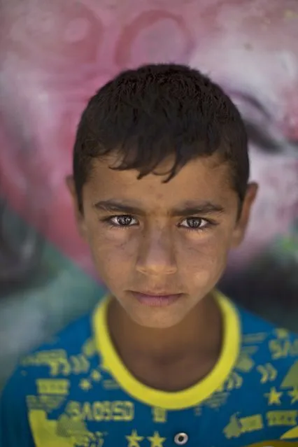 In this Tuesday, July 29, 2014 photo, Syrian refugee Hatem, 13, poses for a picture at Zaatari refugee camp, near the Syrian border, in Mafraq, Jordan. Some children work in Zaatari, while the lucky attend school at the camp. (Photo by Muhammed Muheisen/AP Photo)