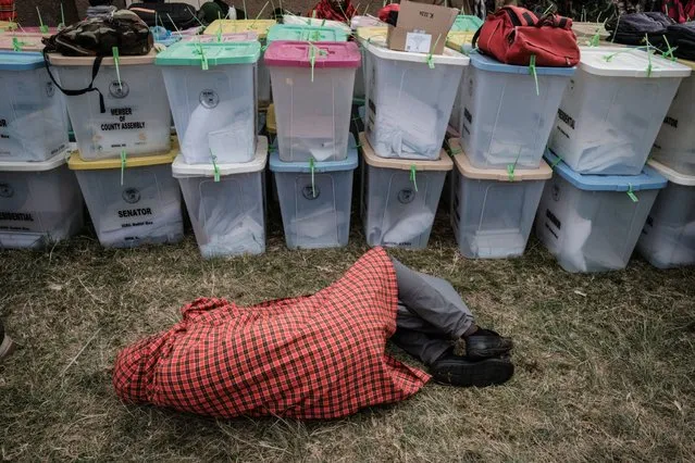Presiding officers sleeps next to ballot boxes as they wait to return all electoral materials following Kenya's general election at the tallying center in Kilgoris on August 10, 2022. (Photo by Yasuyoshi Chiba/AFP Photo)
