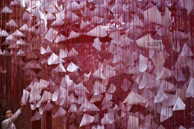 A visitor looks at an installation art called “Tell me your Story” by Japanese artist Chiharu Shiota in Pristina on August 16, 2022, at the 14th edition of the European Nomadic biennale held in Kosovo. (Photo by Armend Nimani/AFP Photo)