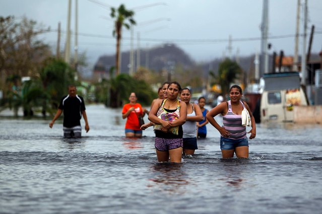 People walk on a flooded street in the aftermath of Hurricane Maria in San Juan, Puerto Rico on September 22, 2017. Puerto Rico battled dangerous floods Friday after Hurricane Maria ravaged the island, as rescuers raced against time to reach residents trapped in their homes and the death toll climbed to 33. Puerto Rico Governor Ricardo Rossello called Maria the most devastating storm in a century after it destroyed the US territory' s electricity and telecommunications infrastructure. (Photo by Ricardo Arduengo/AFP Photo)