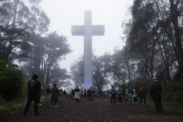 People gather at the Mount Davidson cross in San Francisco, Sunday, April 12, 2020. Mount Davidson's annual Easter Sunrise Service was canceled for San Francisco's shelter in place orders over coronavirus concers. (Photo by Jeff Chiu/AP Photo)