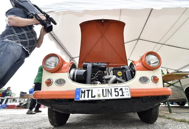 A journalist takes a video of a Trabant car as fans of the East German Trabant car gather for their 7th annual get-together on August 23, 2014 in Zwickau, Germany. Hundreds of Trabant enthusiasts arrived to spend the weekend admiring each others cars, trading stories and enjoying activities. The Trabant, dinky and small by modern standards, was the iconic car produced in former communist East Germany and today has a strong cult following. (Photo by Matthias Rietschel/Getty Images)