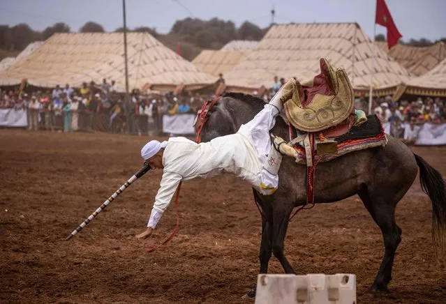 A Moroccan rider falls off his horse as he performs during a Moussem culture and heritage festival in the capital Rabat, on August 27,2022. (Photo by Fadel Senna/AFP Photo)