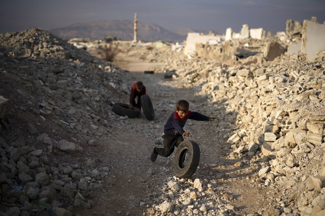 Kids play with tires amid the rubble of homes that were destroyed during the civil war at the Al-Asali neighbourhood in Damascus, Syria, Monday, January 6, 2025. (Photo by Leo Correa/AP Photo)