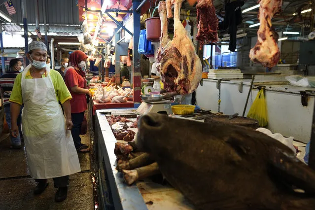 A poultry butcher wearing a face mask to help curb the spread of the coronavirus waits for customers at a wet market in downtown Kuala Lumpur, Malaysia, Friday, April 24, 2020. Malaysia, along with neighboring Singapore and Brunei, has banned popular Ramadan bazaars where food, drinks and clothing are sold in congested open-air markets or road-side stalls. The bazaars are a source of key income for many small traders, some who have shifted their businesses online. (Photo by Vincent Thian/AP Photo)