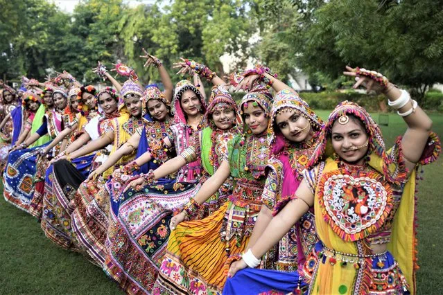 Indian women wearing traditional attire, pose for photographs as they practice Garba, the traditional dance of Gujarat state, ahead of Navratri festival in Ahmedabad, India, Sunday, September 18, 2022. The Hindu festival of Navratri or nine nights will begin from September 26. (Photo by Ajit Solanki/AP Photo)