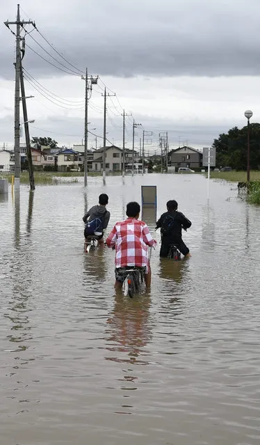 Young boys sit of their bicycles in a street flooded due to heavy rain generated by typhoon Etau in a residential area of Koshigaya, Saitama prefecture, north of Tokyo, Japan, 10 September 2015. (Photo by Franck Robichon/EPA)