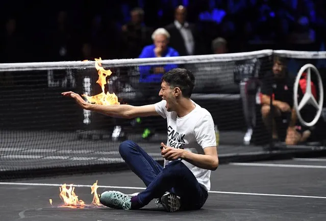 A climate change activist protests against UK private jets while lighting his right arm on fire during the Laver Cup tennis tournament at the O2 Arena in London, Britain, 23 September 2022. (Photo by Andy Rain/EPA/EFE)