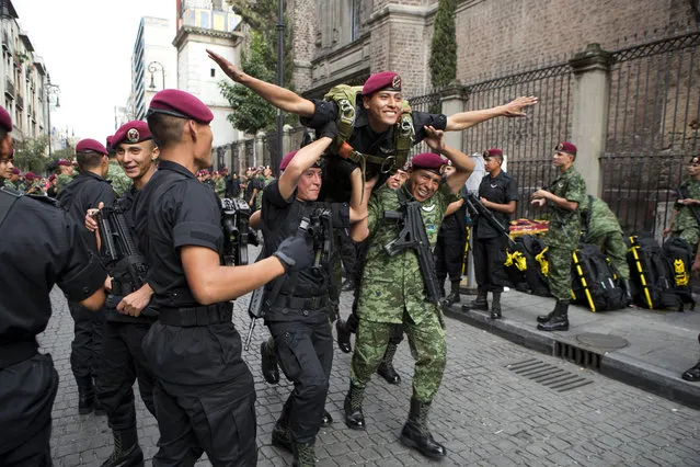 Members of a parachutist group run carrying a soldier, as they joke around ahead of the start of the Independence Day parade by Mexico's Armed Forces, in central Mexico City, Mexico, Tuesday, September 16, 2014. Mexico is marking the 204th anniversary of its independence from Spain. (Photo by Rebecca Blackwell/AP Photo)