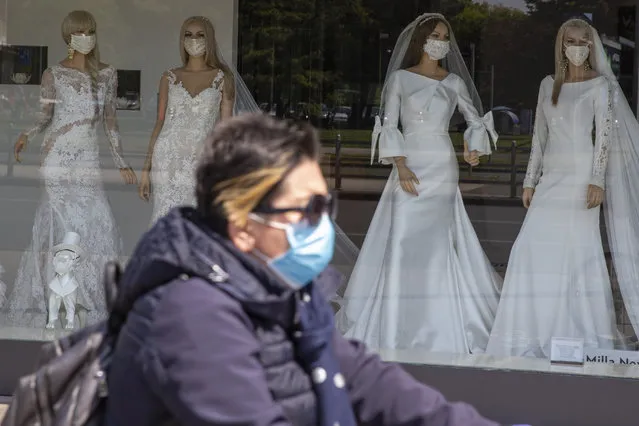 A cyclist wearing a protective mask to protect against coronavirus rides past a wedding dress store with mannequins wearing face masks, in Zagreb, Croatia, Thursday, April 23, 2020. The store is closed because of Covid-19 lockdown. (Photo by Darko Bandic/AP Photo)