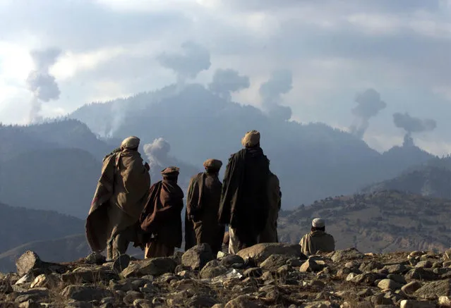 Anti-Taliban Afghan fighters watch several explosions from U.S. bombings in the Tora Bora mountains in Afghanistan December 16, 2001. (Photo by Erik de Castro/Reuters)